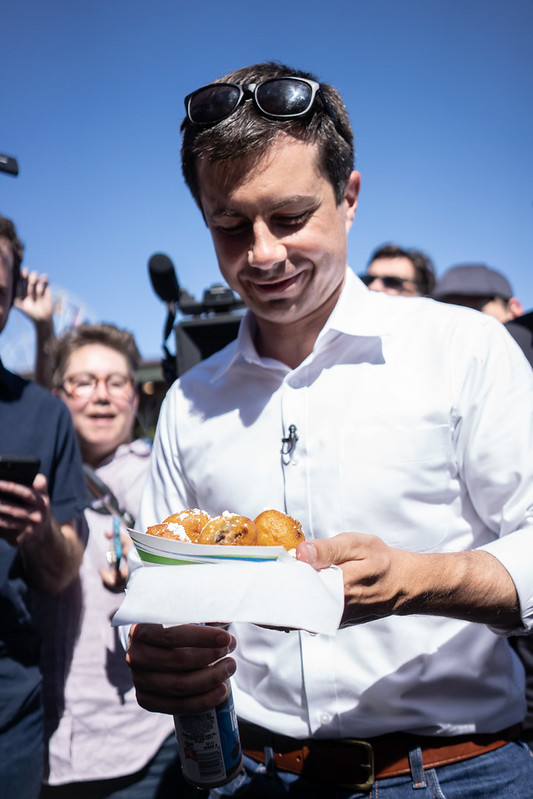 Pete Buttigieg smiles as he looks at a plate of fried oreos.